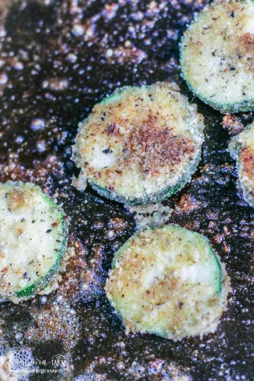 Frying parmesan zucchini in a cast iron skillet.