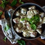 creamed herb potatoes in a bowl with fresh herbs on top and more to the side with a spoon