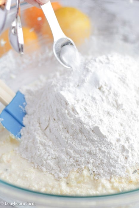 Dry ingredients being poured into a bowl of creamed ingredients.