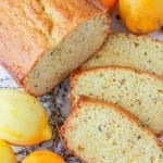 Three slices of citrus thyme bread next to a sliced loaf of bread with a lemon.