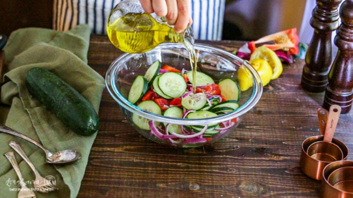Adding olive oil to the easy cucumber salad. 