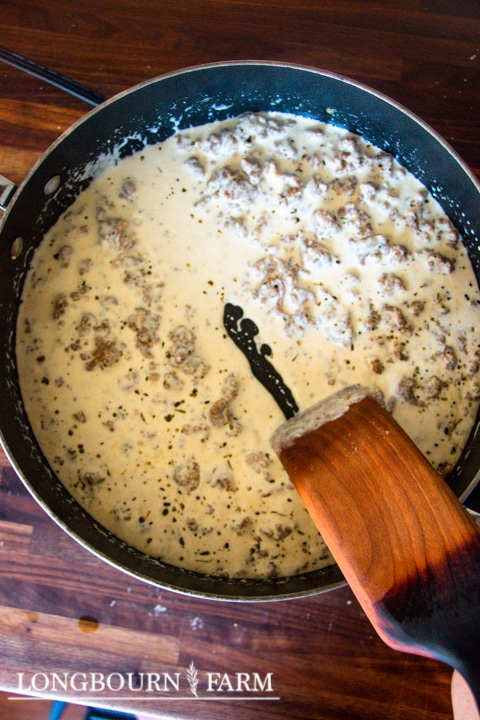 skillet full of sausage alfredo sauce that has been thickened