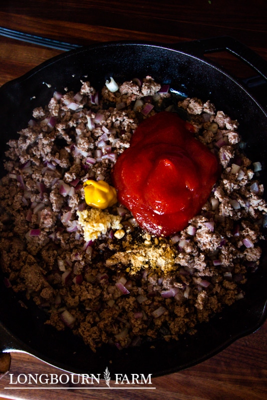 cooked ground meat in a cast iron with ketchip mustard and other ingredients for sloppy joe sauce