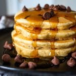 side view of chocolate chip pancakes with syrup and scattered chocolate chips