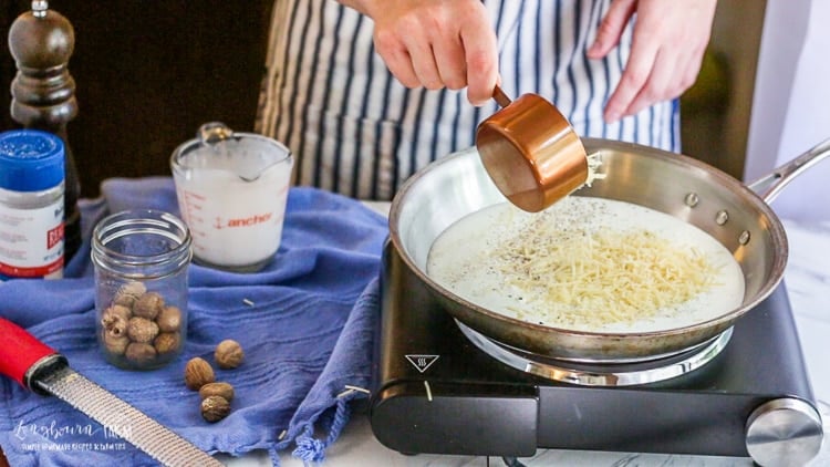 Adding parmesan cheese to easy homemade alfredo sauce.