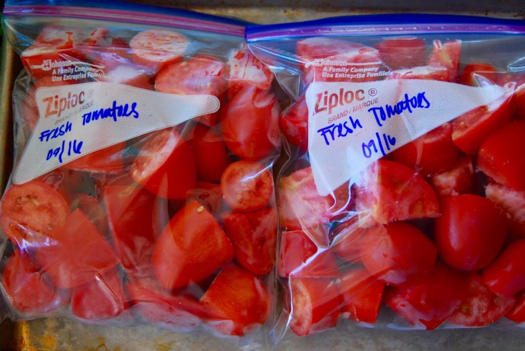 Top view of bagged, flash-frozen, fresh tomatoes ready for the freezer. Easy way to preserve tomatoes.