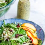 Creamy poppy seed dressing behind a plate of quick spinach salad.