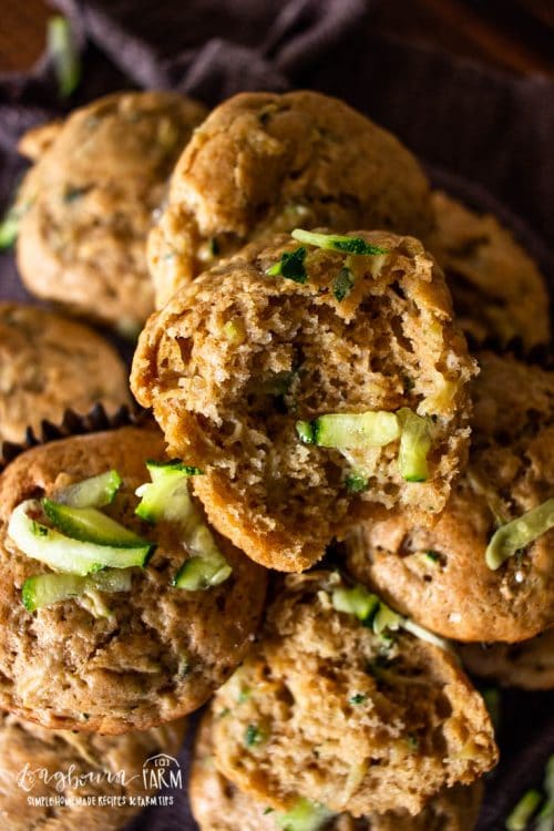 a pile of baked zucchini muffins with some shredded zucchini scattered on top