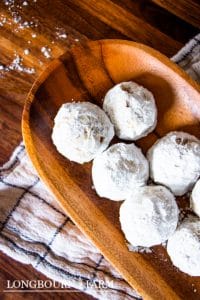 a wooden oval platter filled with buttery pecan snowball cookies