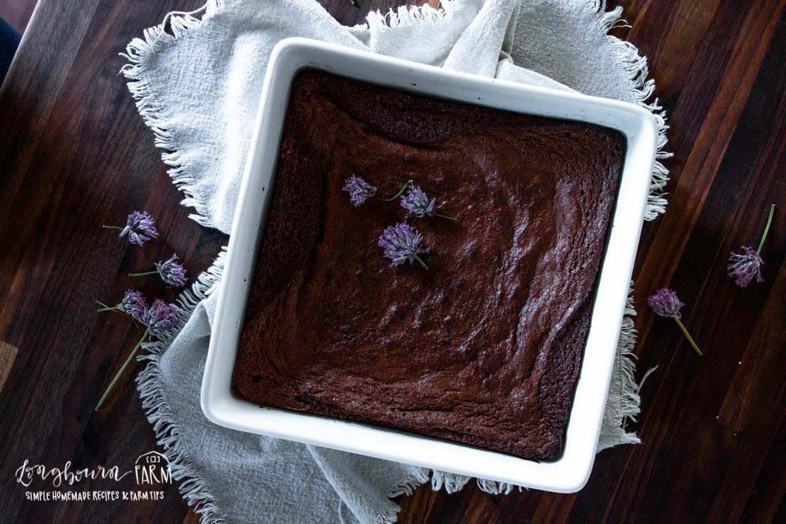 baked brownie in white square pan with purple flowers on top
