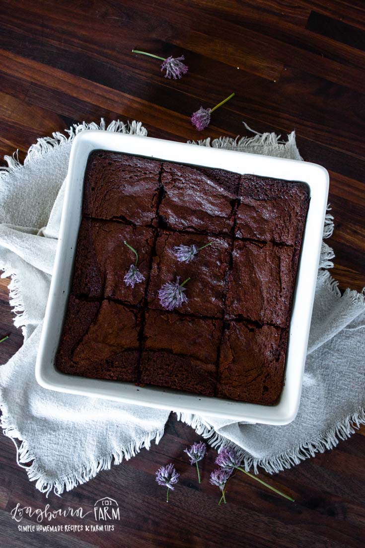 a baking dish full of sliced brownie squares and topped with purple flowers