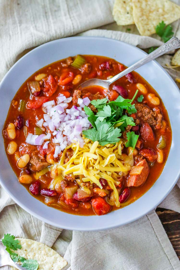 Spoon in the homemade chili in a grey bowl.
