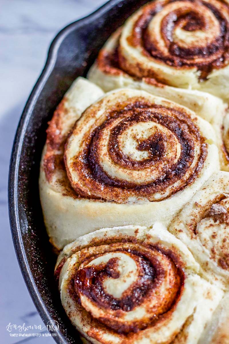 Close-up of a baked homemade cinnamon roll in a cast iron skillet.