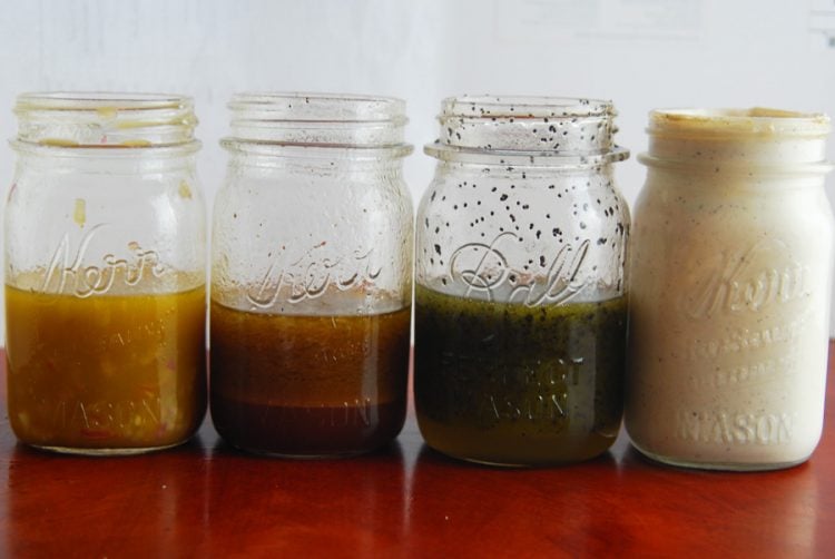 Homemade salad dressing in 4 jars in a row.