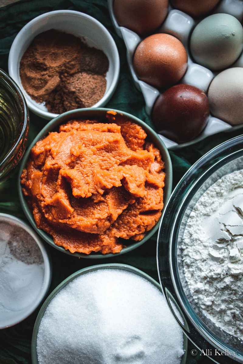 ingredients for layered pumpkin cake, eggs, pumpkin puree, flour, sugar and spices all in bowls.