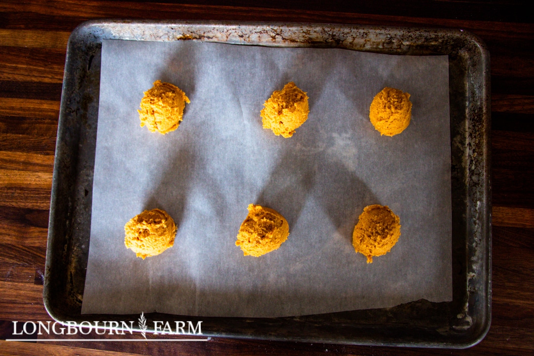 scooped pumpkin sugar cookie dough on parchment lined baking sheet