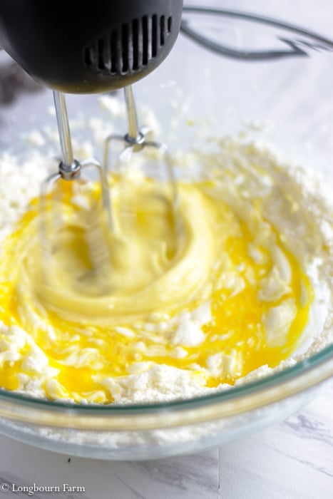 Beaters mixing an egg into creamed butter and sugar.