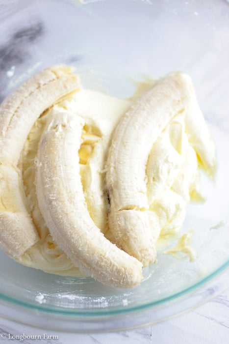 Ripe bananas in a bowl over creamed butter, sugar and eggs for chocolate chip banana recipe.