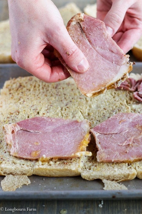 Spreading ham onto the ham and cheese sliders. 