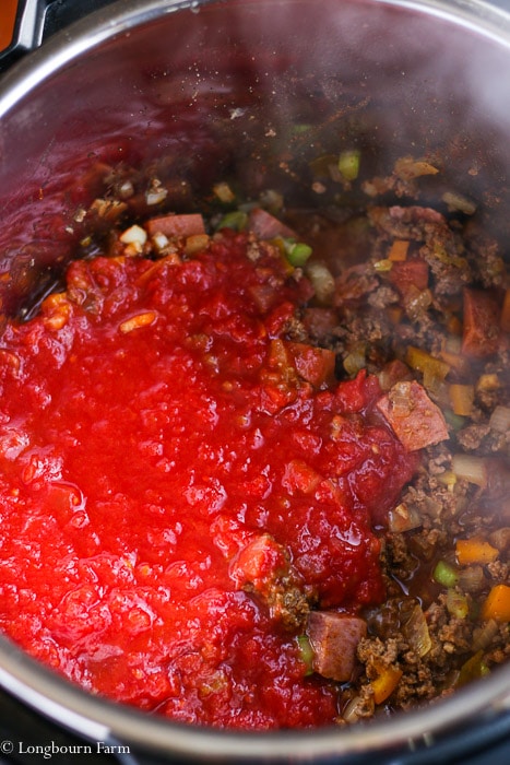 Crushed tomatoes on top of all the other ingredients for Instant Pot Chili. 