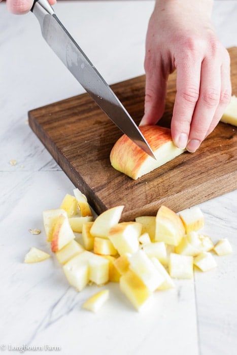 Chopping an apple on a small wooden cutting board.