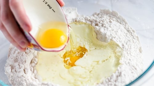 Pouring an egg into the other ingredients for cinnamon muffins.