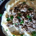 an upclose view of ground stroganoff on a bed of mashed potatoes