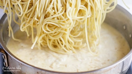 Adding spaghetti into the lemon cream sauce.