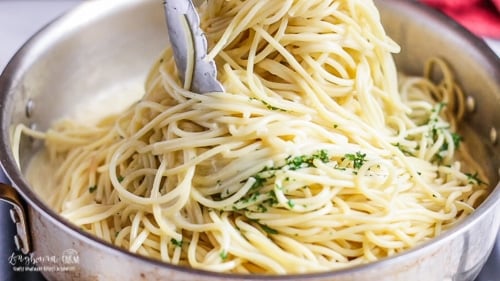 Tossing the spaghetti into the lemon cream sauce with tongs.