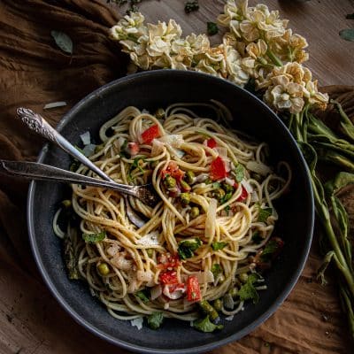 pasta primavera with shredded parmesan in a pan with two forks