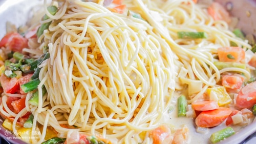 Adding pasta to pasta primavera recipe.