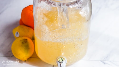 Adding water to citrus lemonade to finish making the recipe.
