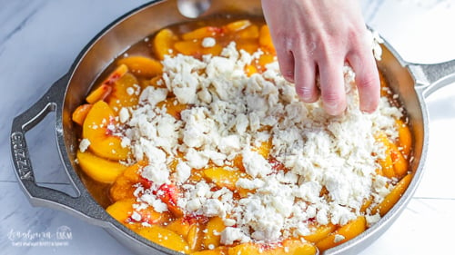 Spreading crumb topping on top of peaches for easy peach cobbler.