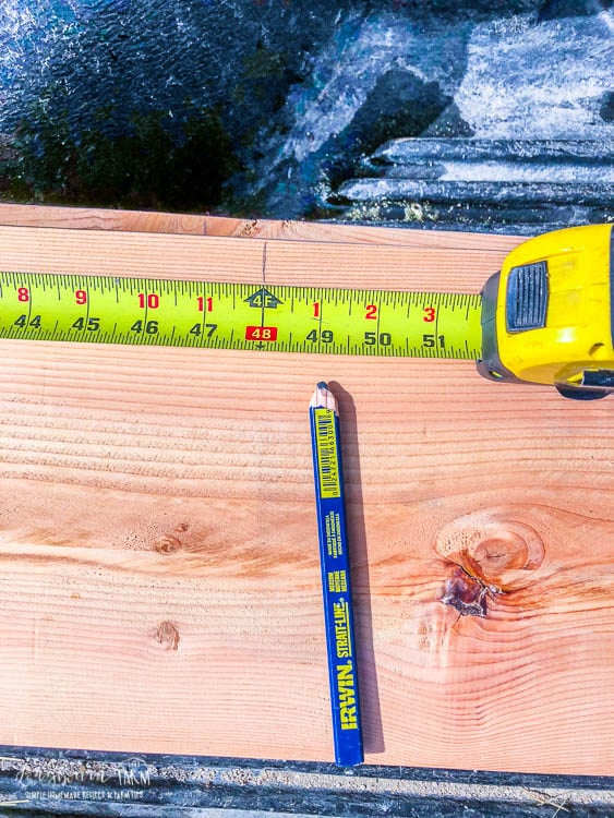 Measuring 4 feet on an 8 foot piece of wood for building raised planter beds. 