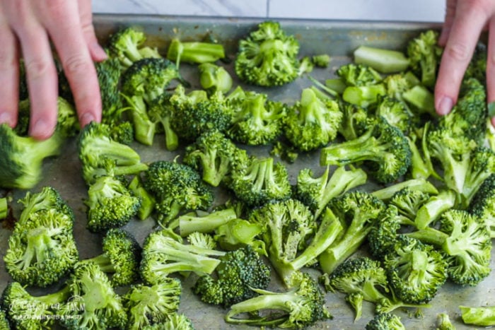 Spreading oven roasted broccoli into a single layer.
