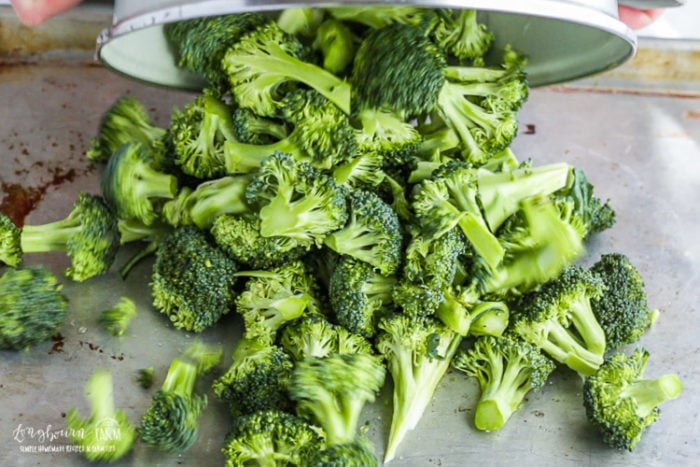 Pouring broccoli onto a sheet pan.