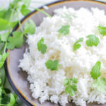 Top angled view of a plate of white rice with cilantro sprinkled on top.