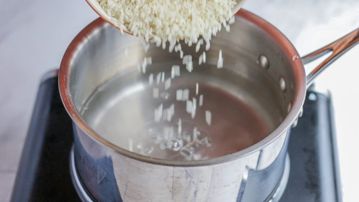 Pouring dried white rice into a pot. 
