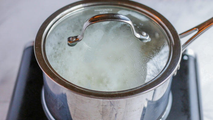Water simmering in a covered pot cooking the white rice recipe.