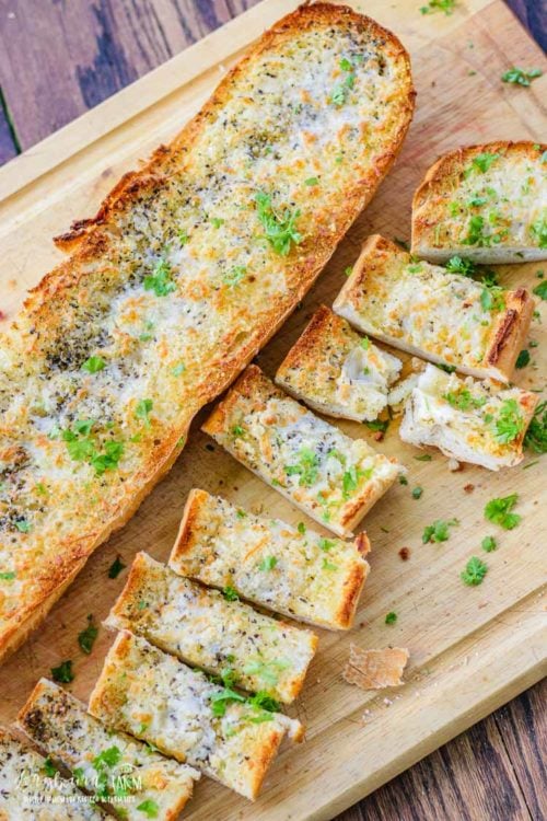 Cheesy garlic bread recipe cut up on a cutting board.