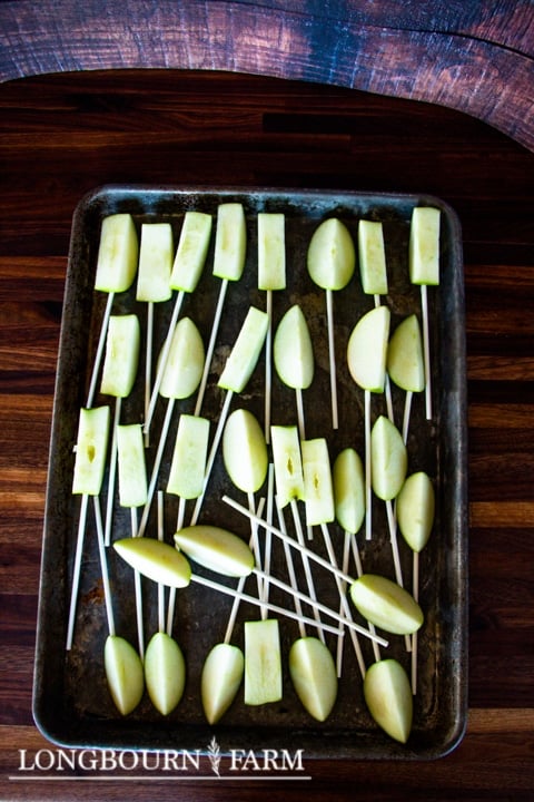 apple slices on sticks on a baking sheet