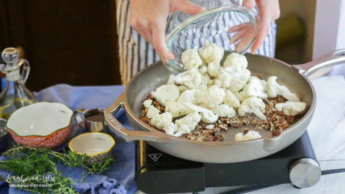 Adding cauliflower to the GRIZZLY cast iron pan. 