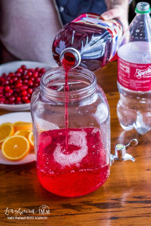 Adding cranberry juice to drink container for Christmas punch recipe. 