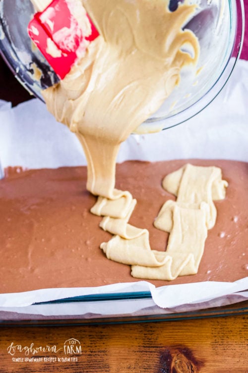 Pouring peanut butter layer onto peanut butter chocolate fudge. 