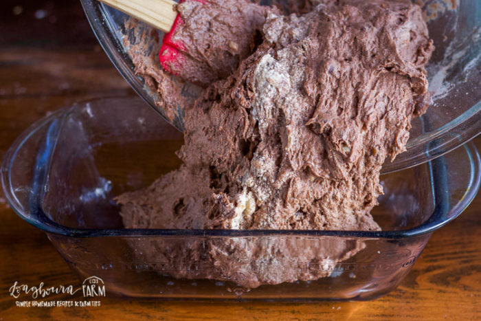 Pouring chocolate banana bread batter into a loaf pan. 