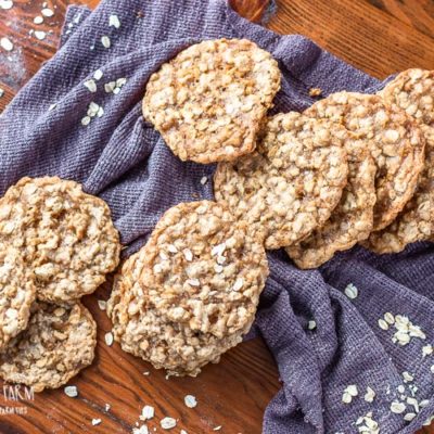Chewy homemade oatmeal cookies in a pile on a table with a towel.