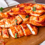 Oven baked bbq chicken on a cutting board.