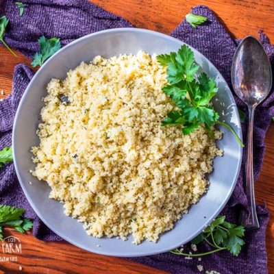 Moroccan couscous in a grey bowl garnished with parsley.