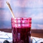 a mason jar filled with blackberry syrup next to fresh blackberries
