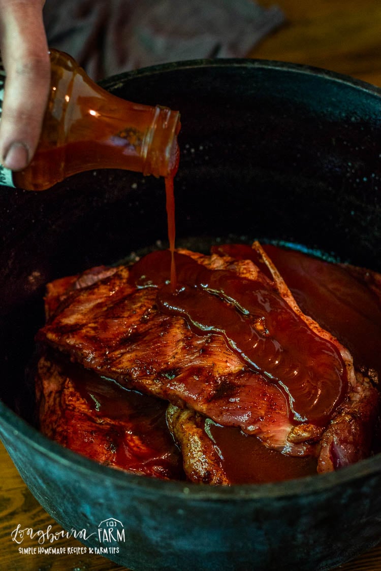 Pouring BBQ sauce over pork ribs.